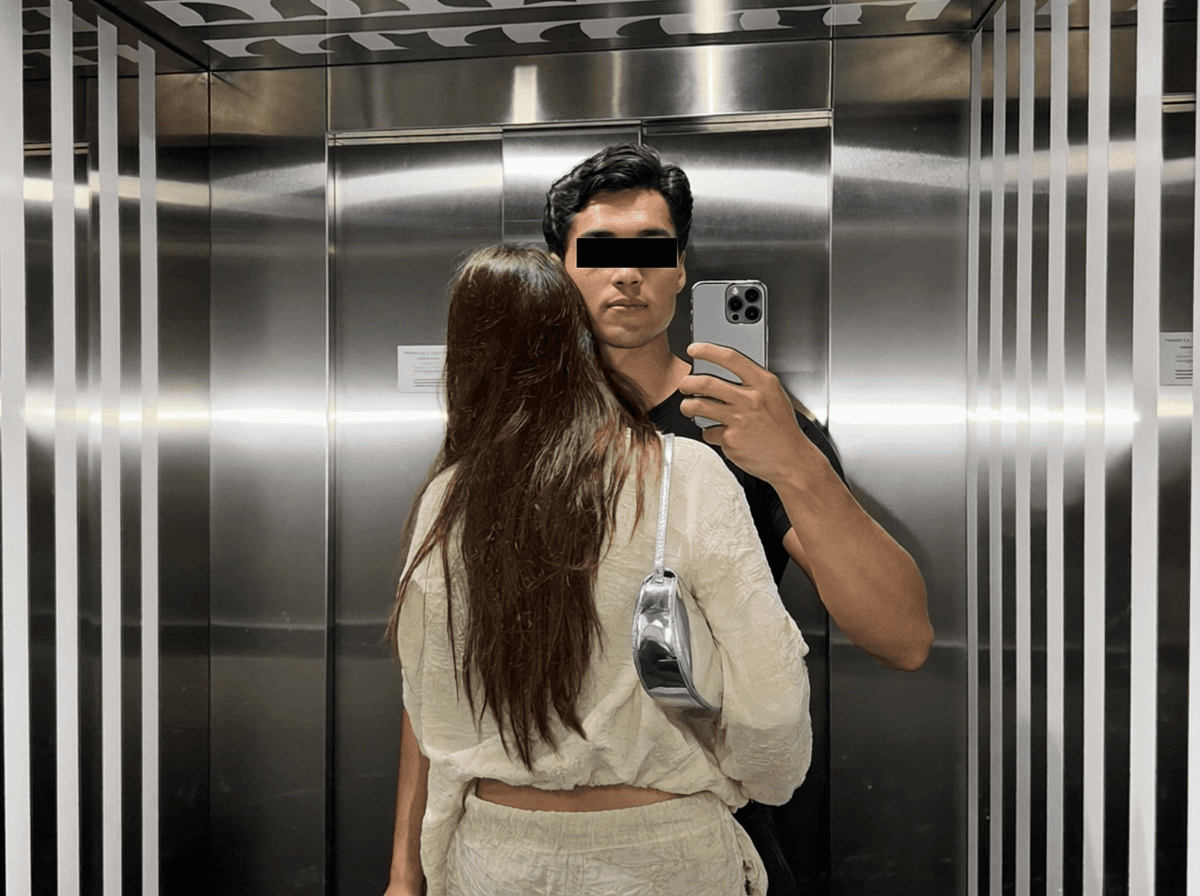 A couple taking a mirror selfie in an elevator